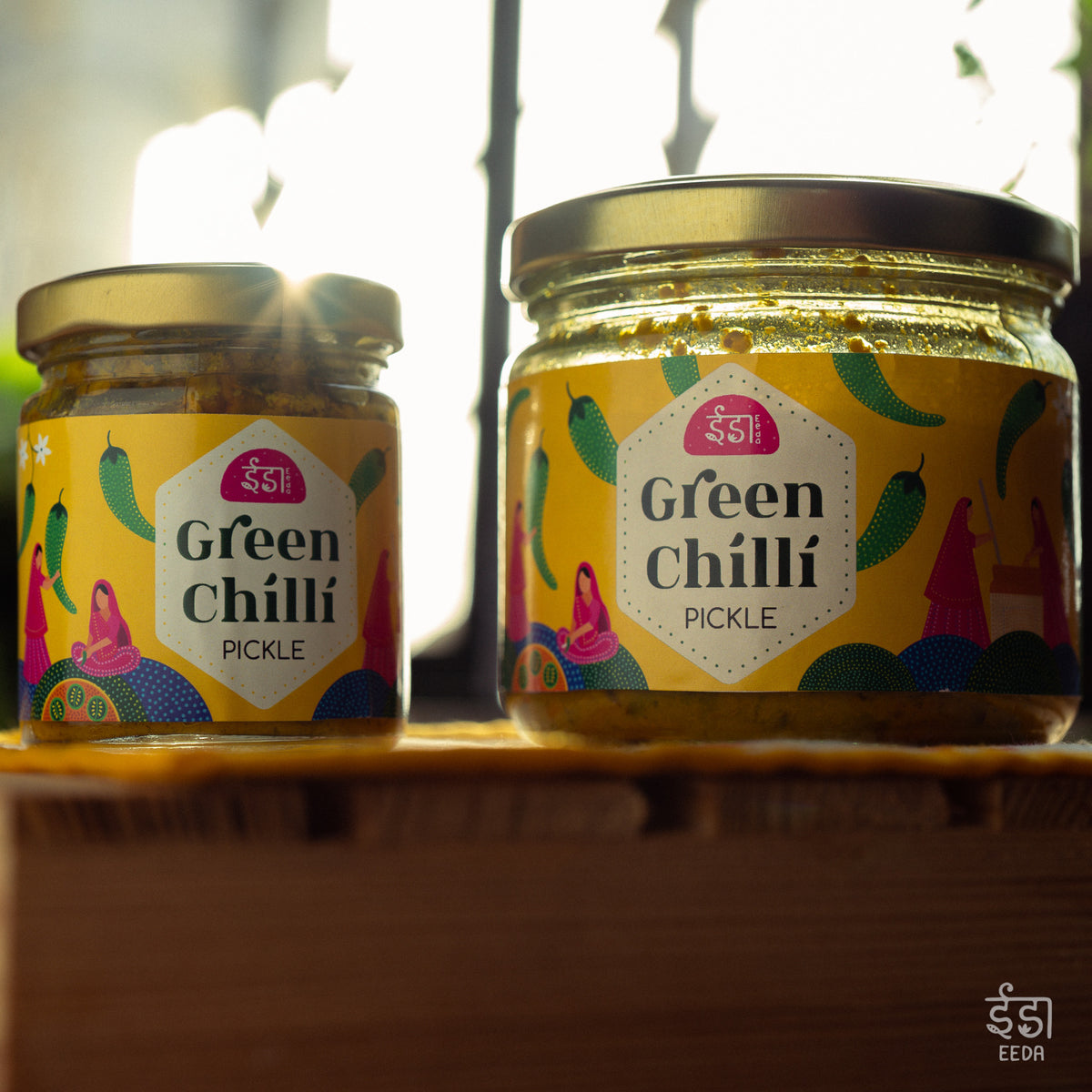 Two jars of Eeda Hari Mirch Achar on a wooden shelf