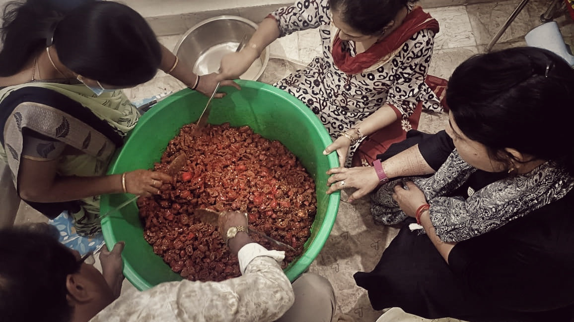 Women mixing a large tub of achar by hand